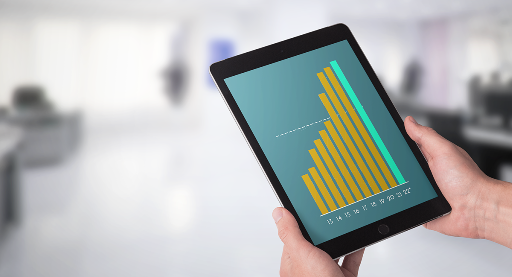 A person holds a mobile tablet device which shows a bar chart depicting growth, representing the growing personalised photo industry.